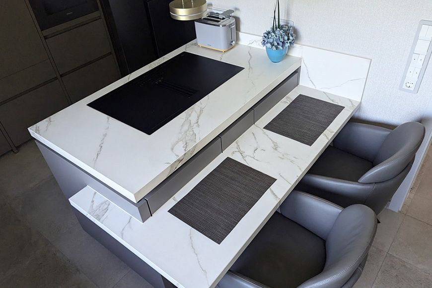 Eine Küche mit einer Marmorarbeitsplatte und zwei Stühlen.