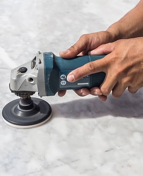 Graue Natursteinplatte wird mithilfe einer Poliermaschine bearbeitet